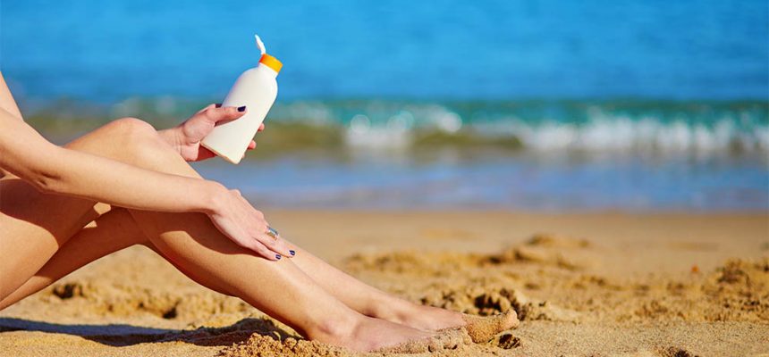 Beautiful young woman applying sunscreen on her legs
