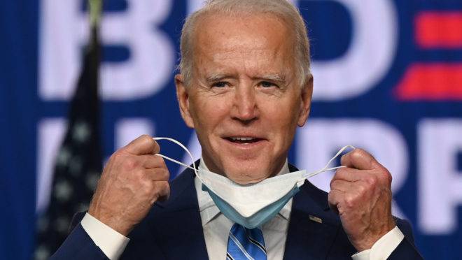 Democratic Presidential candidate Joe Biden removes his mask before speaking at the Chase Center in Wilmington, Delaware on November 4, 2020. - President Donald Trump and Democratic challenger Joe Biden are squaring off for what could be a legal battle for the White House, running neck-and-neck in the electoral vote count, and several battleground states still in play on November 4. (Photo by JIM WATSON / AFP)