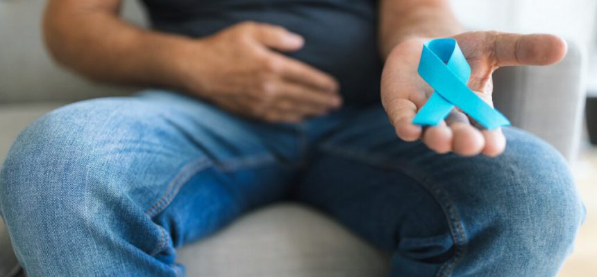 Senior man holding a blue cancer awareness ribbon in hand